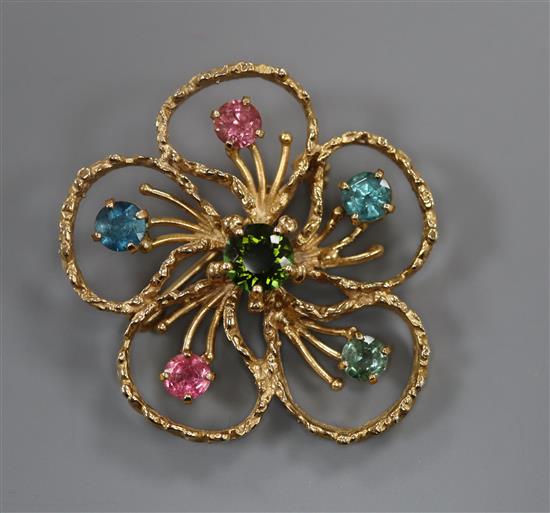 An openwork flower brooch centred by a green tourmaline with five gem-set stamens, 9ct gold textured setting, 38mm.